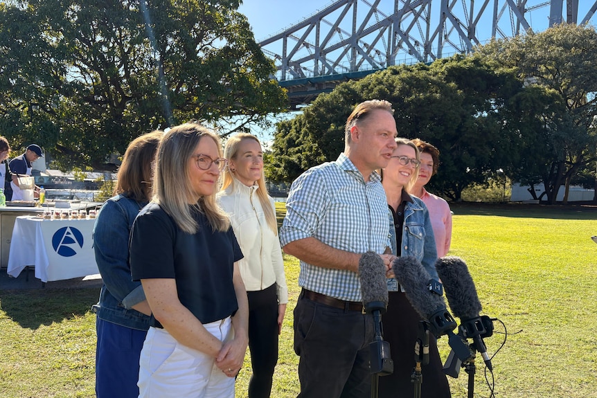 Adrian Schrinner speaking at press conference with Story Bridge in background.
