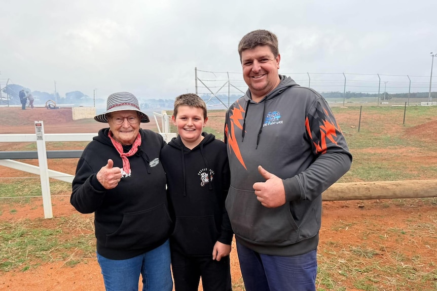 A woman and young boy both in black jumpers next to a man with a grey jumper with orange lightening bolts