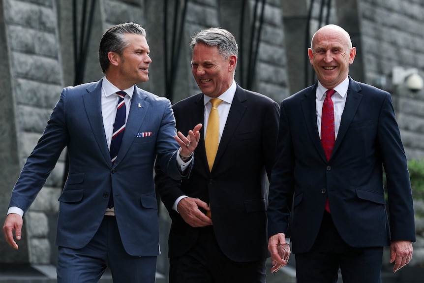 Three men in suits walking and laughing.