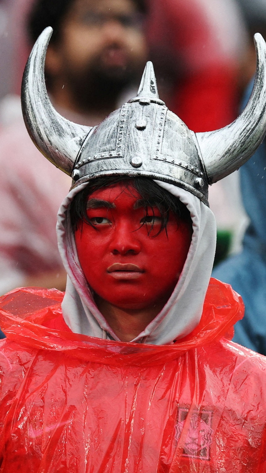a man wearing bright red face paint and a horned helmet