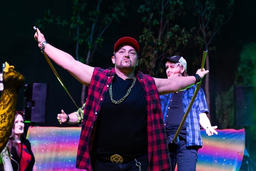 A drag king holding tape measures.