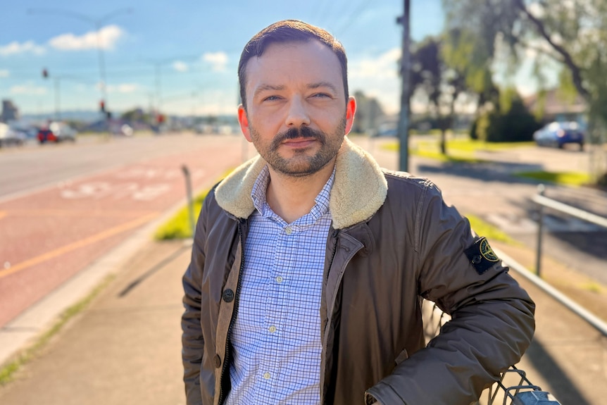 Man in leather jacket stands near highway