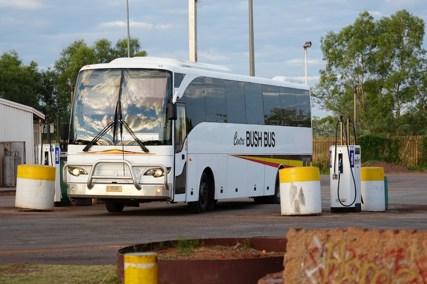 A white large passenger bus at a petrol station, with the words' Centre Bush Bus' printed on the vehicle.