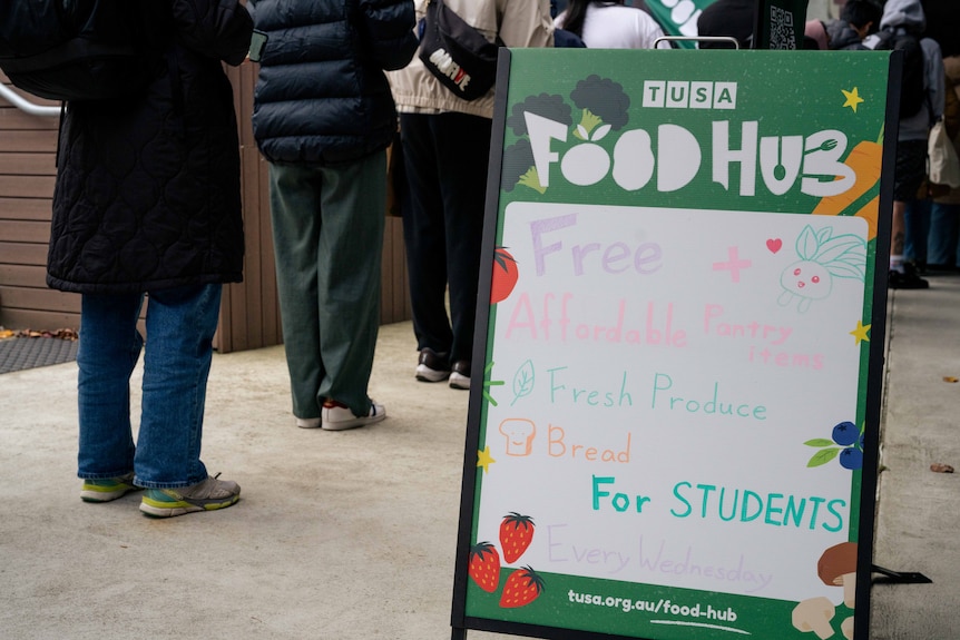 Students lining up with a sign that says "FOOD HUB"