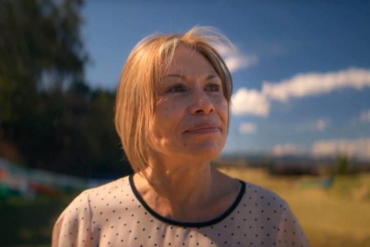 Tonya Lee as an adult stands on a beach looking pensively into the distance