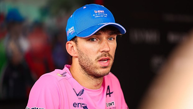 A man in a pink Alpine F1 shirt speaks to media.