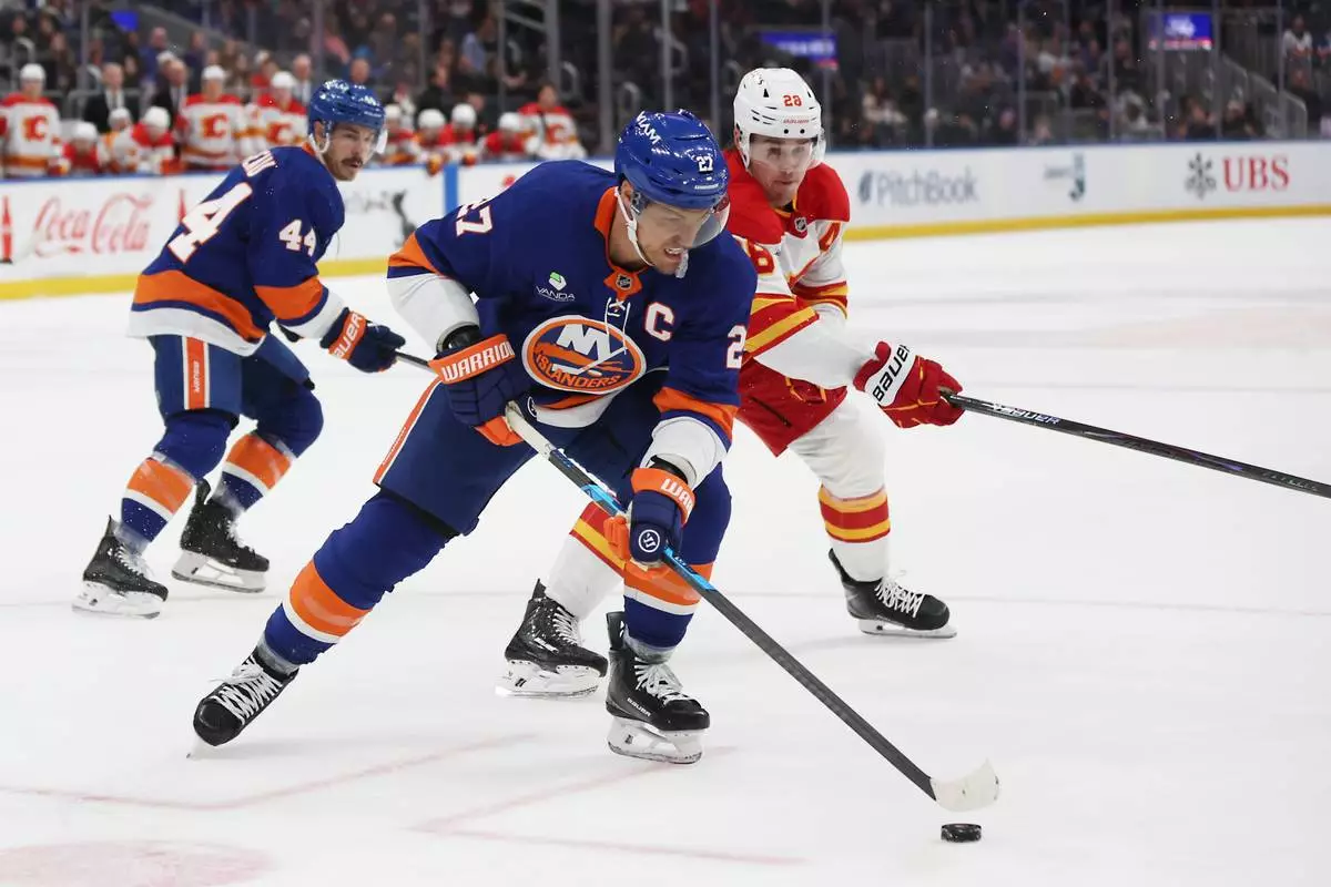 FILE - New York Islanders left wing Anders Lee (27) gets to the puck before Calgary Flames defenseman Zach Whitecloud (28) during the third period of an NHL hockey game, March 14, 2026, in Elmont, N.Y. (AP Photo/Heather Khalifa, File)