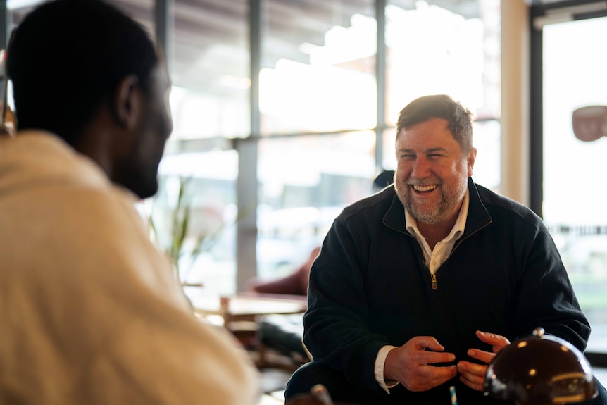 Two men chat at a cafe