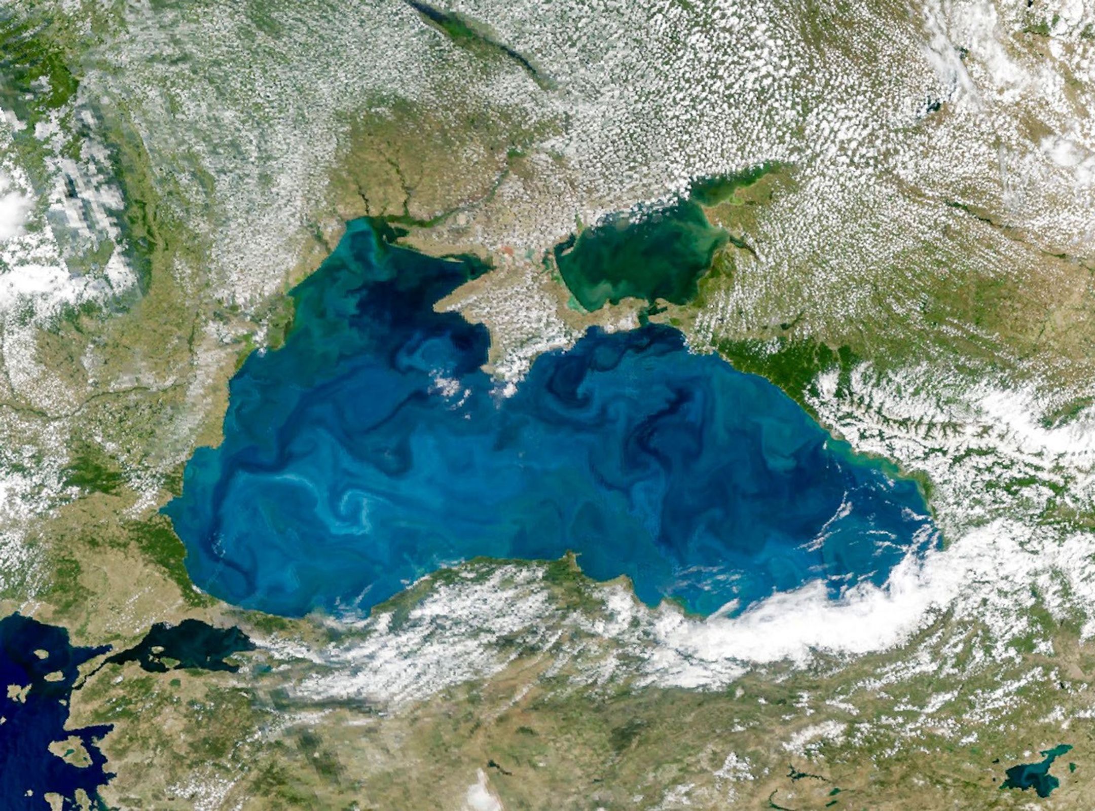 A satellite image shows swirling turquoise water in the Black Sea, centered within the frame.