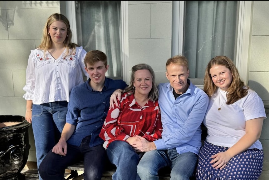 Richard Scolyer with his wife and three children sitting on a seat in front of a house