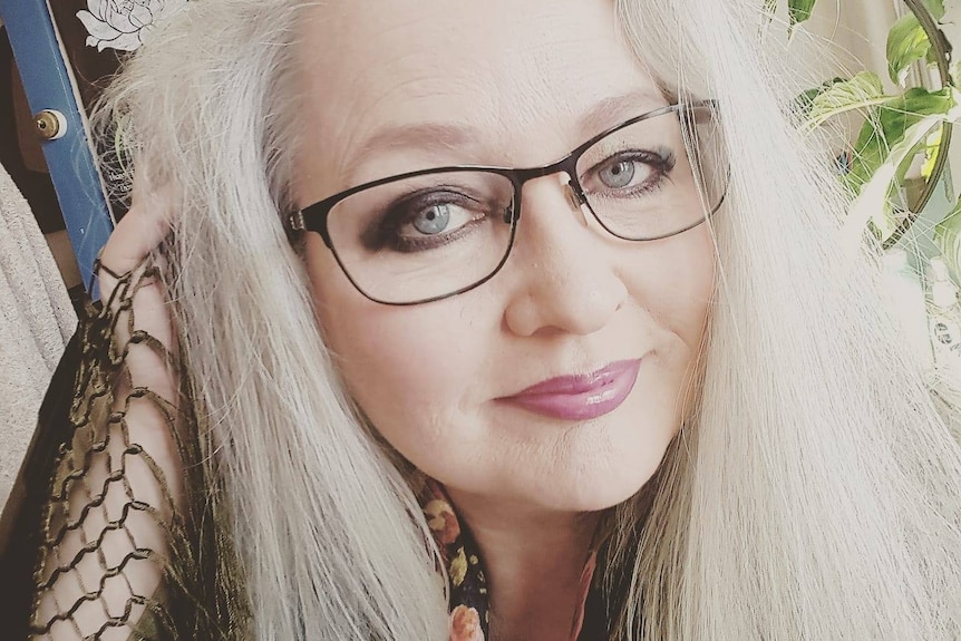 Sarah Baker has silver hair and wears glasses