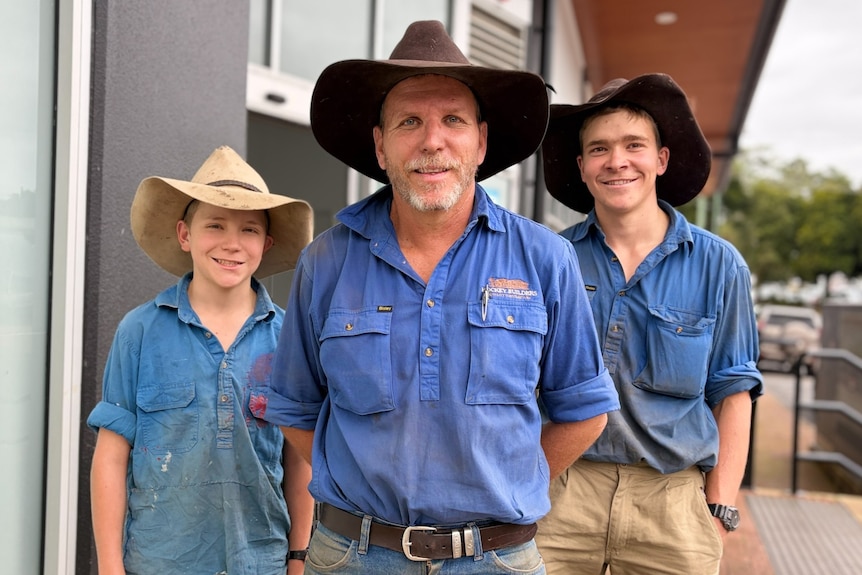Man flanked by two boys, all wearing broad-brimmed hats