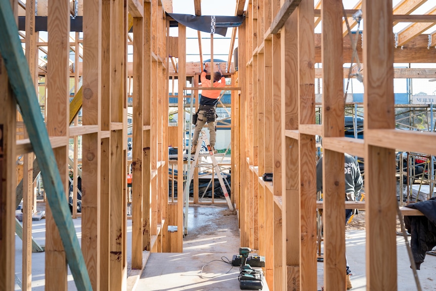 A construction worker is working at the site of building a house. 