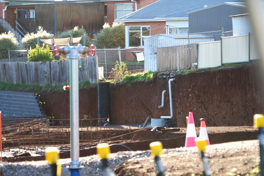 A construction site shows steep excavation close to a neighbouring property fence.