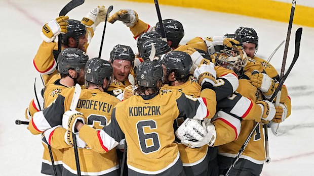 A group of hockey players hug on the ice.