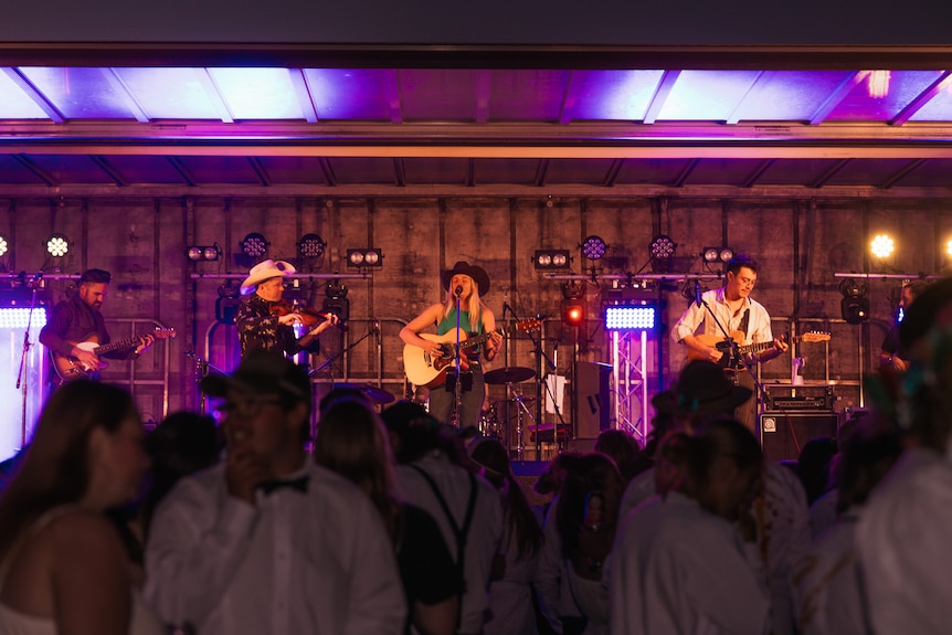 four musicians on the stage with a crowd in the foreground