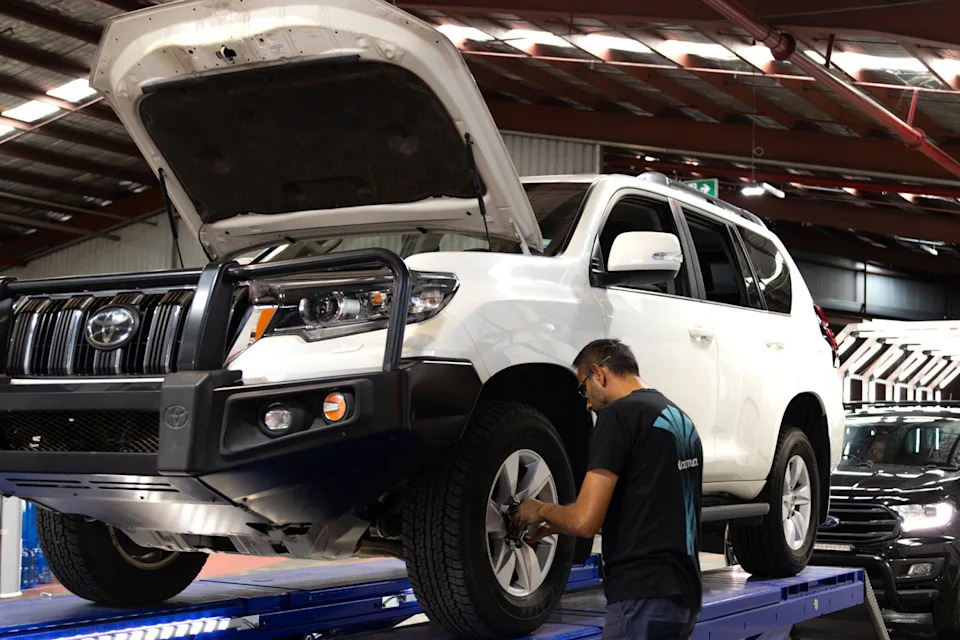 A mechanic works on a Toyota 4wd inside a workshop.