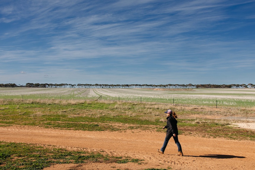 A young woman walking along a dirt road at a farm in WA.