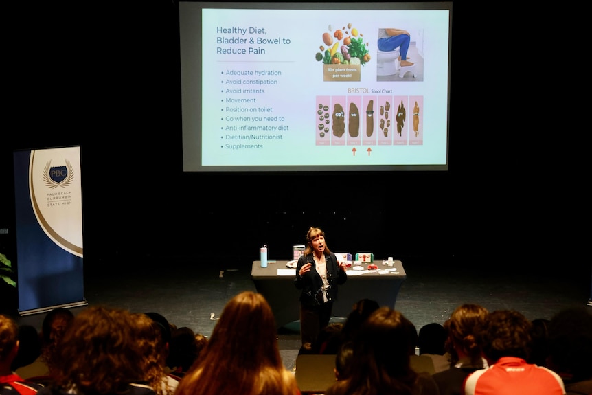 A room of school students and a woman speaking