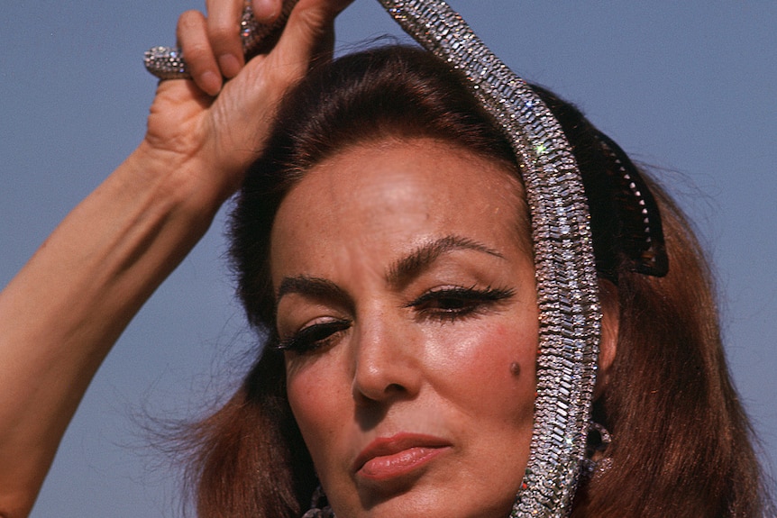 María Félix holding her snake Cartier necklace on her head