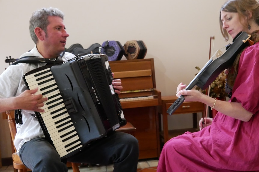 Two people seated playing instruments
