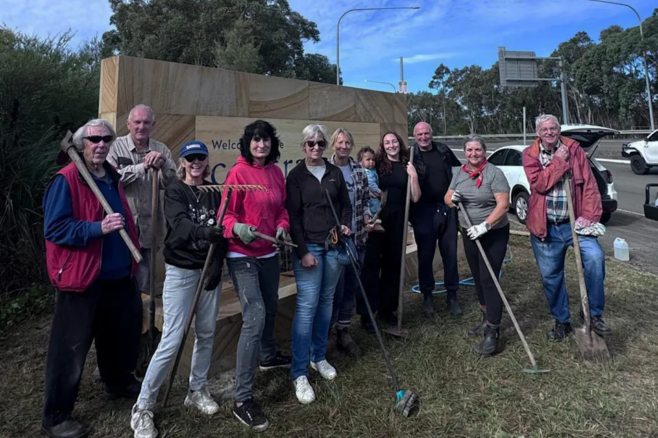 Kariong Progress Association members in front of a renovated Welcome to the Central Coast sign.