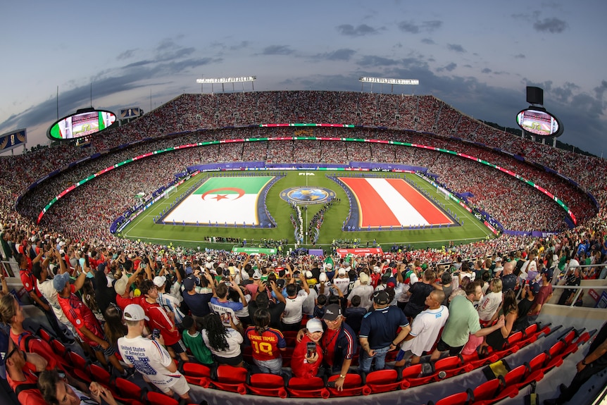 A long angle shot of a sports stadium with flags on the grass