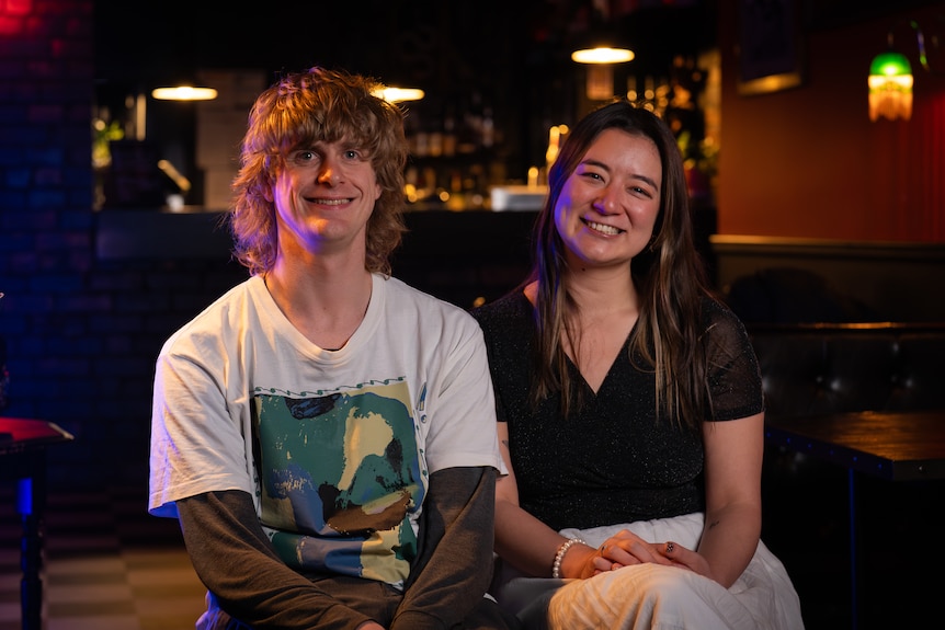 Charlie Pyecroft and Emi Doi sit next to each other and smile.