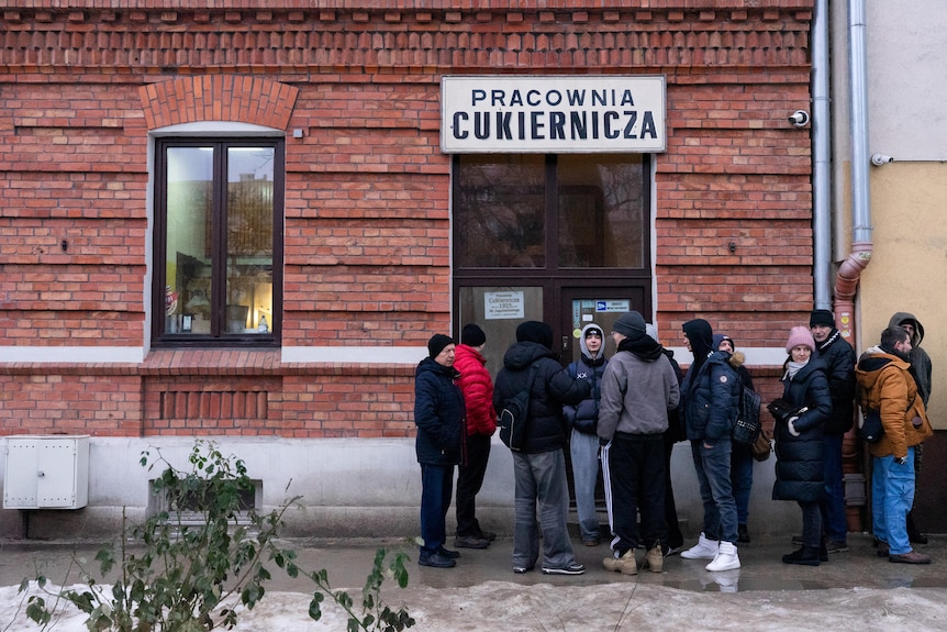 People stand in a queue outside a bakery.