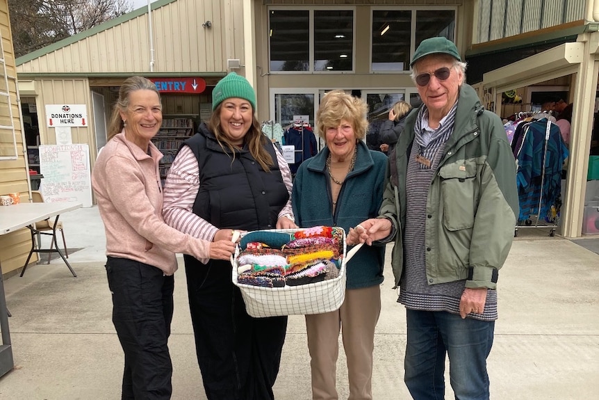 a group of people pose with a bundle of knits
