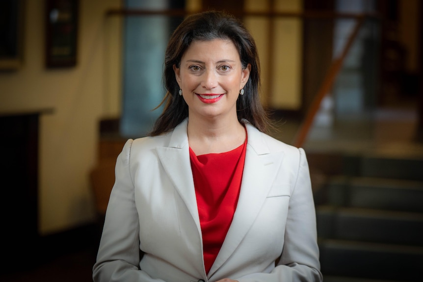 A woman dressed in a suit smiles at the camera
