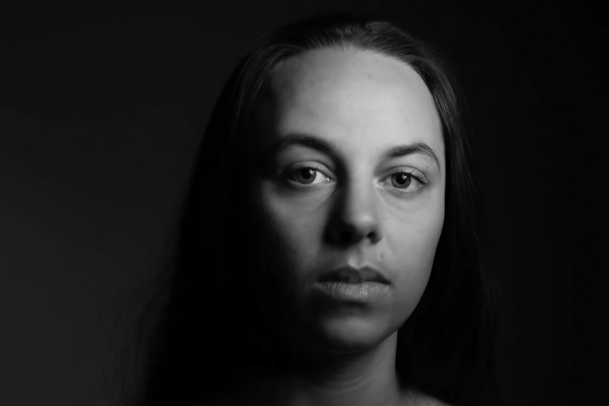 A black-and-white portrait of Carly Sheppard, an Indigenous woman in her late 30s, with a serious expression.