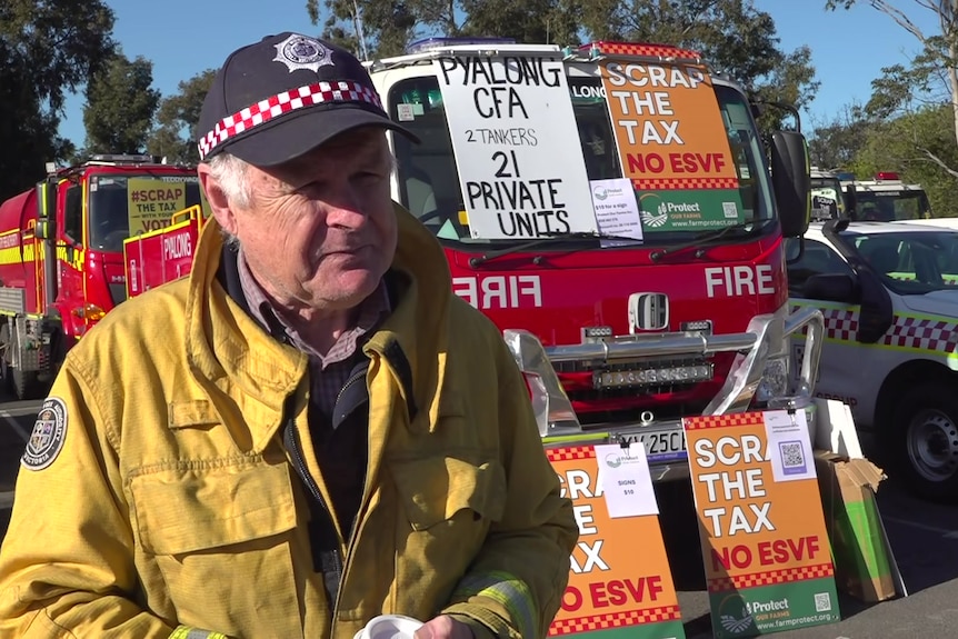 Chris Cooke wears yellow CFA jacket and is standing in front of a fire truck.