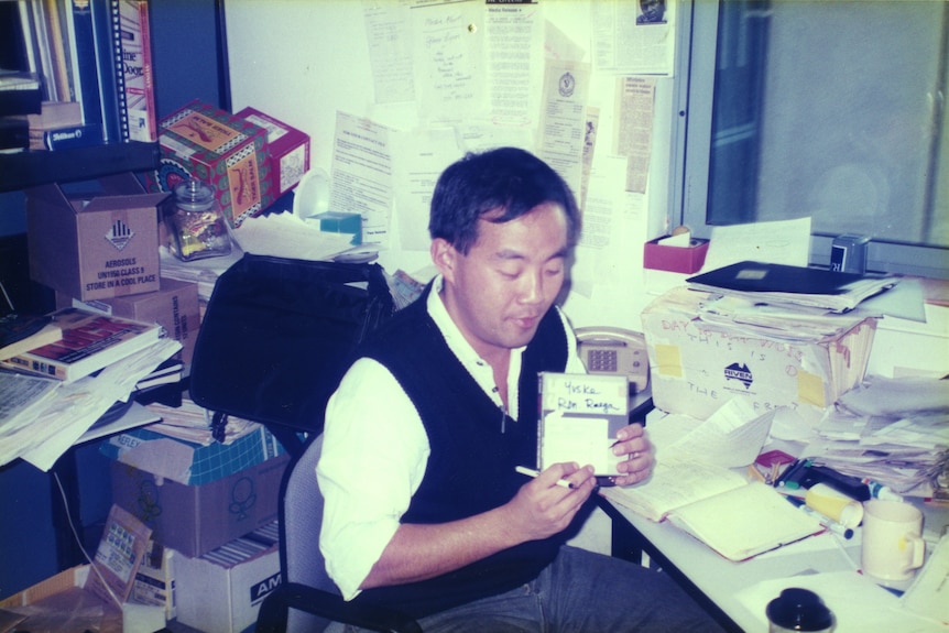 a man holds a tape while seated at a desk