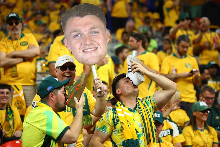 australian football fans - two drinking from a shoe - while another holds a giant carboard hary souttar head