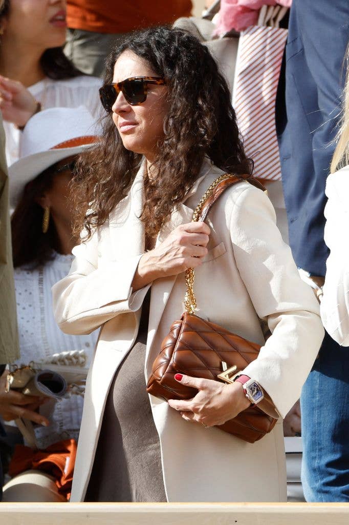 Rafael Nadal's wife Xisca Perello in a beige coat and grey dress, expectant with their second child Miquel.