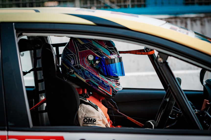 A woman in a racing car with a helmet on.