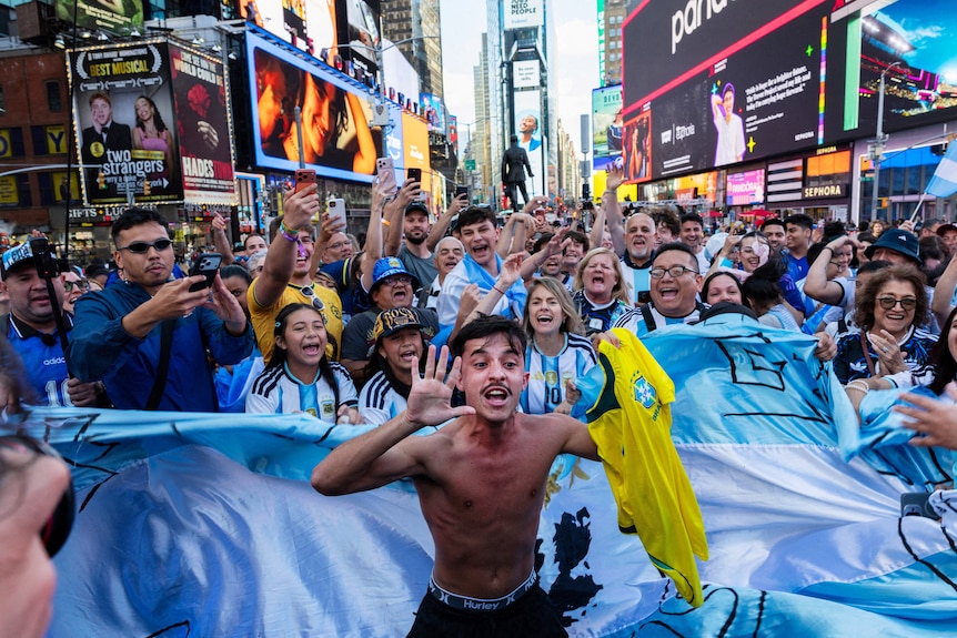 a large crowd of argentinian fans gather in times square - awash with light blue jerseys