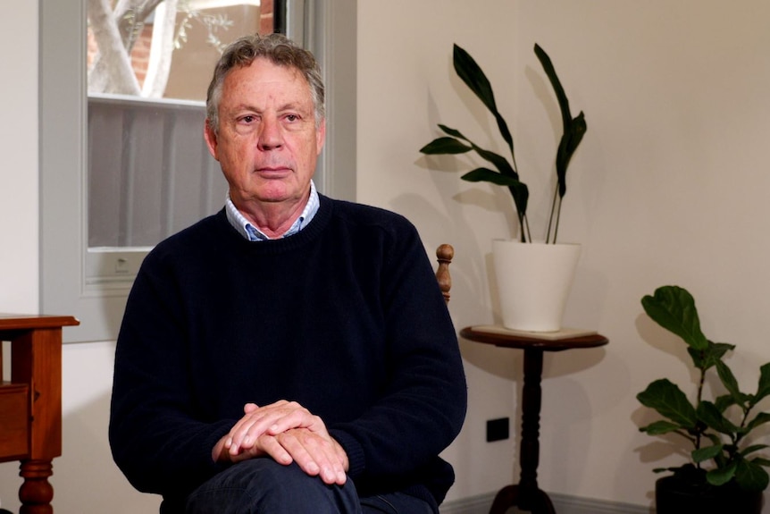 A man sist on a chair and look past the camera