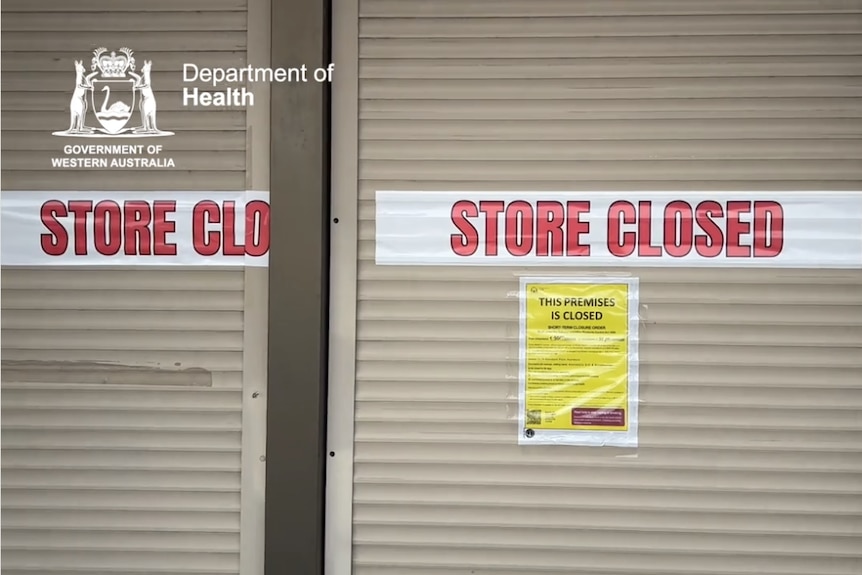 A 'store closed' sign in front of a roller-shutter door.