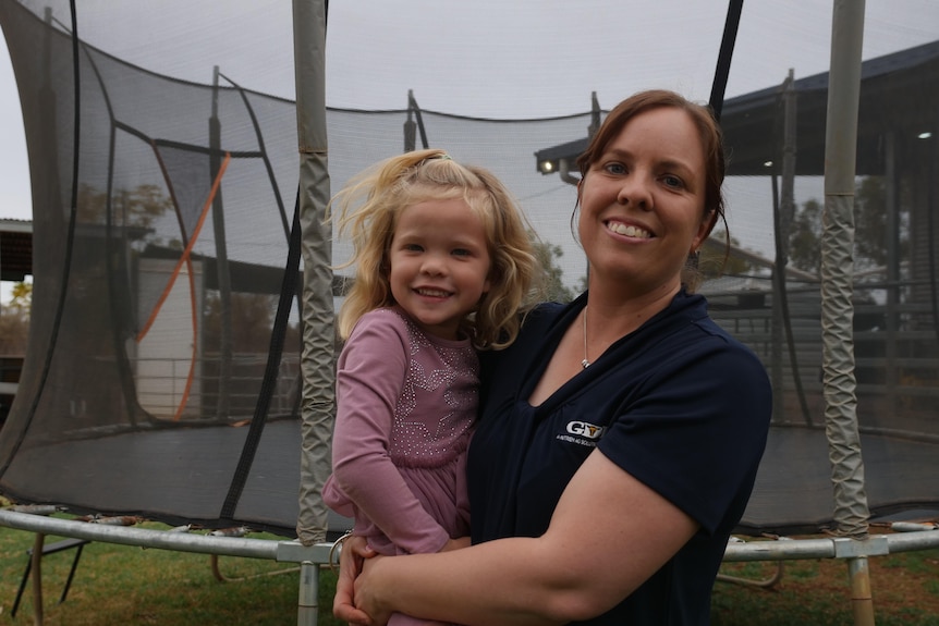 women holding small child smiles at camera