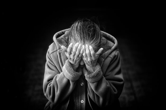 Older person with hands covering face showing signs of dementia