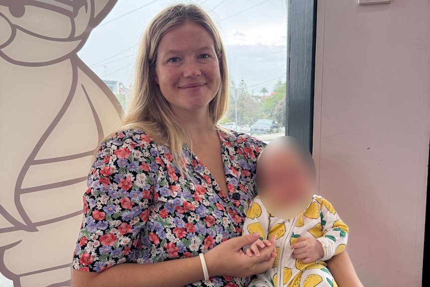 Sydney mother and Coogee local, Leah Stewart, who was mauled by a shark holds a baby and looks at the camera