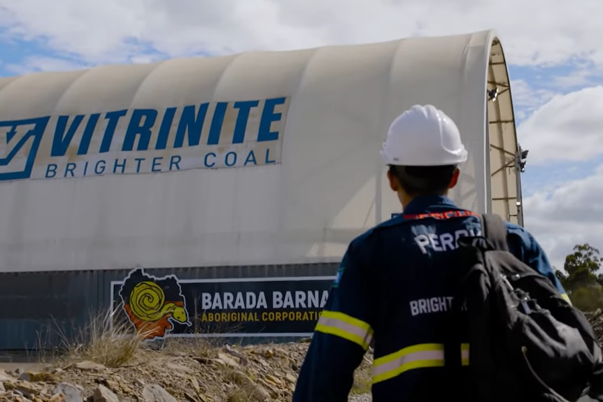 A woman walking towards a larger pavilion with the Vitrinite logo on the side