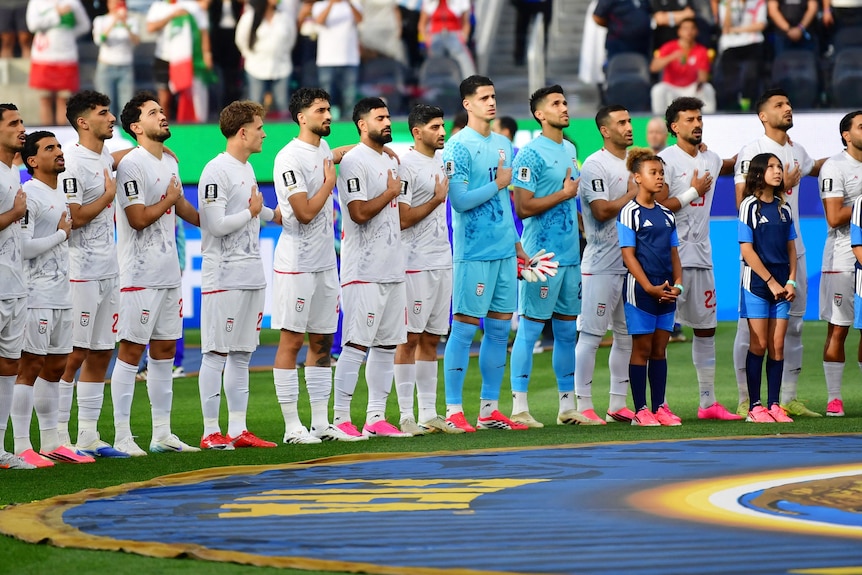 Iran men's players line up and sing the national anthem with hands on hearts