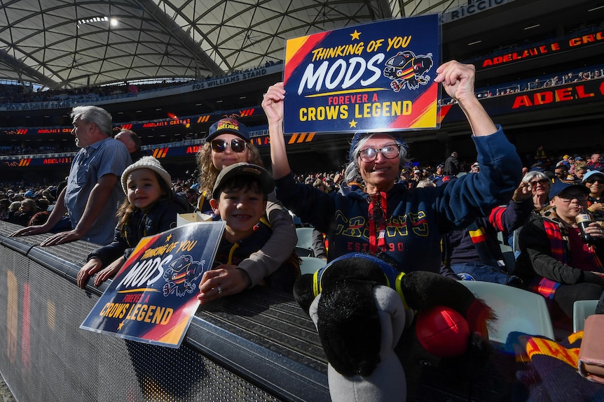 Adelaide Crows supporters hold a sign saying THINKING OF YOU MODS CROWS LEGEND