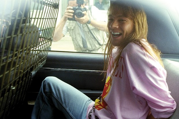 Guns N' Roses lead singer Axl Rose sits handcuffed in the back of a police car after he was arrested at Kennedy Airport upon his return from a European concert tour. R