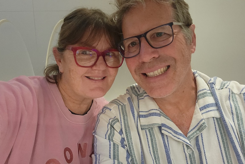 A photo of a woman wearing a pink sweater and glasses, next to a man with a striped shirt wearing glasses