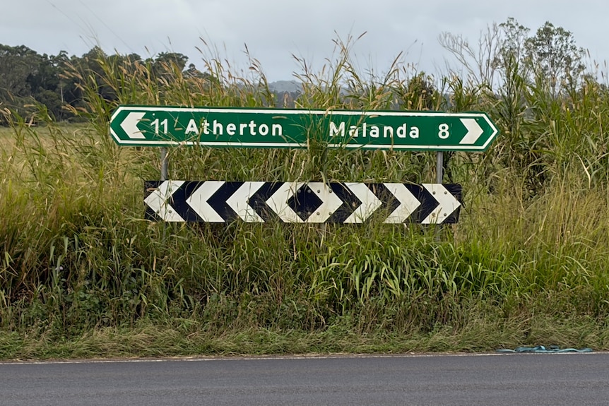 A green road sign gives distances to Atherton and Malanda.
