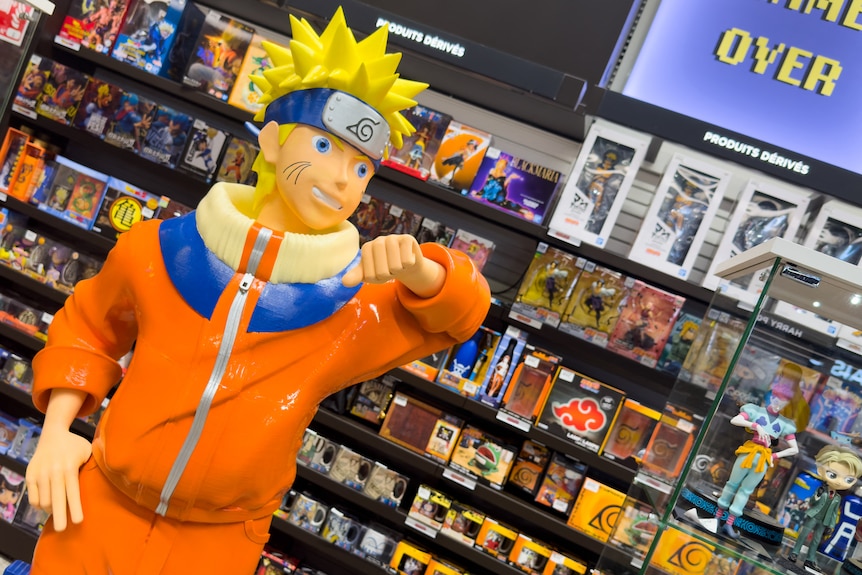 A statue of an anime character with blonde hair and an orange track suit in a shop.